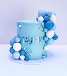 a blue and white cake with balloons on it's side that says taylor in large letters