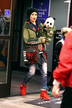 a woman is walking down the street with a panda bear in her hand and wearing red boots