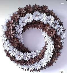 a wreath made out of pine cones and white flowers