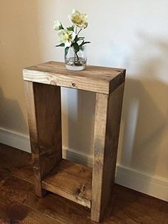 a small wooden table with flowers in a vase on top