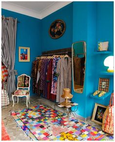 a room with blue walls and colorful rugs on the floor next to a chair