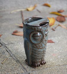 an owl shaped vase sitting on the ground