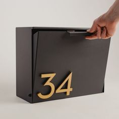 a hand is opening the door to a black box with gold numbers that say 34