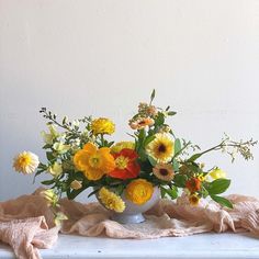 a vase filled with lots of different colored flowers on top of a white table cloth