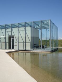 a glass building sitting next to a body of water