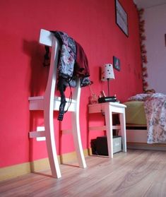 a bedroom with red walls and white furniture on the floor, along with a bed