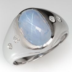 This awesome ring is centered with one (1) oval cabochon cut star sapphire set into a bezel. The shoulders of the ring are each accented with two (2), flush set, round single cut diamonds. The ring measures 13.7mm at the top, rises 8.4mm above the finger, tapering to 4.1mm wide and 1.0mm thick at the base of the shank. This ring is currently a size 6.75. Modern Oval Opal Ring For Formal Occasions, Modern Formal Opal Ring With Cabochon, Modern Formal Cabochon Opal Ring, Formal Modern Opal Cabochon Ring, Fine Jewelry Sapphire Ring With Oval Cabochon, Classic White Gold Cabochons For Anniversary, Oval Diamond Cabochons For Formal Occasions, Oval Cabochon Sapphire Ring With Polished Finish, Modern Cabochon Sapphire Ring For Anniversary