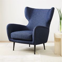 a blue chair sitting next to a plant on top of a white carpeted floor