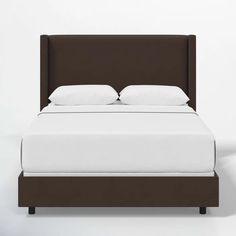 a bed with white sheets and brown headboard