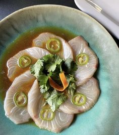 a green bowl filled with food on top of a blue plate next to a knife and fork