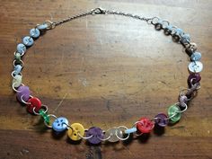 A necklace made out of colorful recycled buttons chained with silver tone jump rings. Multicolor Round Beads Fun Necklace, Colorful Handmade Playful Necklaces, Retro Multicolor Adjustable Necklaces, Adjustable Multicolor Funky Necklace, Hippie Multicolor Hand-strung Necklace, Recycled Buttons, Button Necklace, Button Jewelry, Jump Rings