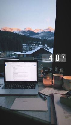 an open laptop computer sitting on top of a desk next to a pen and paper