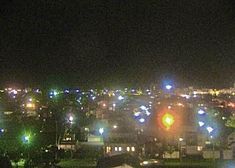 the city lights are brightly lit up in the dark night sky over some buildings and trees