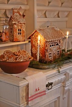 gingerbread houses are displayed on the mantles in front of candles and plates, along with other holiday decorations