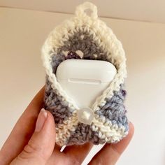 a hand holding a small crocheted object with a button in it's center