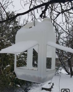 a bird house covered in snow next to trees