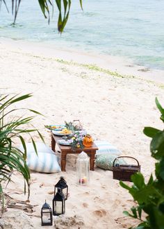 a table on the beach is set up with lanterns