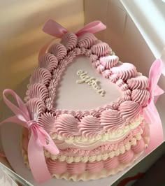 a heart shaped cake in a box with pink ribbon