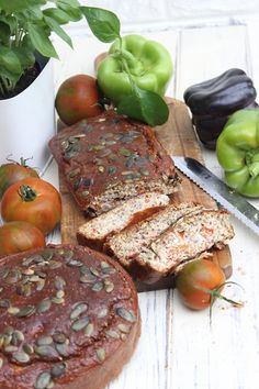 sliced loaf of bread sitting on top of a cutting board next to tomatoes and peppers