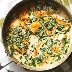 a pan filled with chicken and spinach covered in white sauce on top of a table