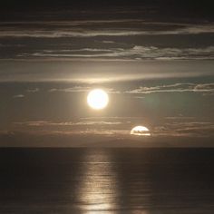 the sun is setting over the ocean with clouds