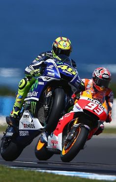 two motorcyclists racing on a track near each other in front of the ocean