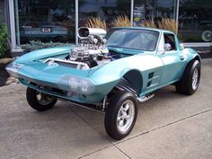 a blue car parked in front of a building with an engine on it's hood