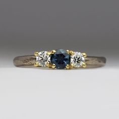 three stone engagement ring with two diamonds on each side and a blue sapphire in the middle