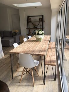 a wooden table sitting in the middle of a living room next to a glass wall