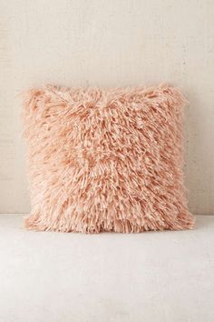 a pink pillow sitting on top of a white couch