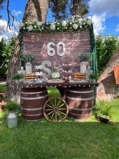 an outdoor dessert table with wine barrels and flowers on the top, surrounded by greenery