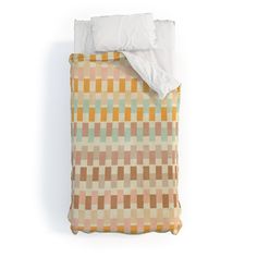 a bed with an orange and green checkered comforter on top of it next to a white pillow