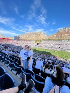 two people standing in the stands at a football game