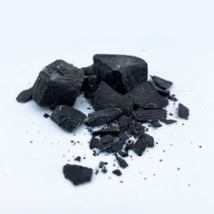 pieces of black coal are on a white surface with some scattered dirt around the edges