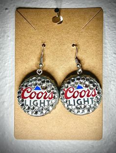 pair of earrings with the words coors light printed on them in red, white and blue