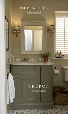 an old white bathroom with gray cabinets and marble counter tops, along with a large mirror above the sink