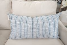 a blue and white pillow sitting on top of a couch next to a vase with flowers