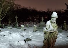 a statue in the middle of a snow covered cemetery