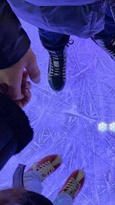 two people standing in front of an ice rink looking down at their feet and shoes