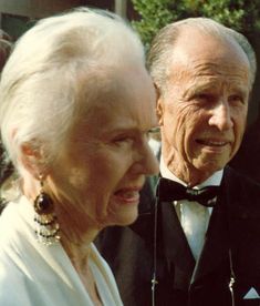 an older man and woman standing next to each other wearing tuxedo's