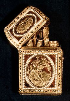 an ornately decorated gold colored lighter on a black background