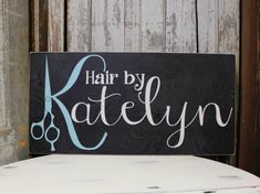 a wooden sign that says hair by katelyn on the side of a white table