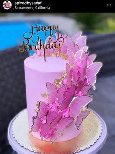 a pink birthday cake with butterflies on top and the words happy birthday written in gold