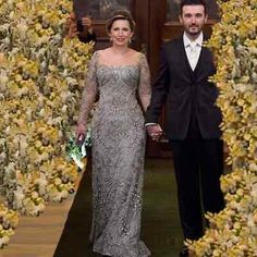 a man and woman in formal wear walking down a hall with yellow flowers on it