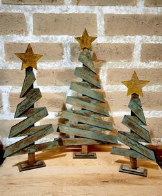 three wooden christmas trees with gold stars on them sitting in front of a brick wall