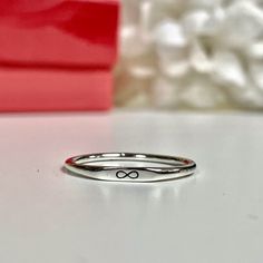 two silver rings sitting on top of a white table next to a red box and some rocks