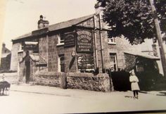 an old black and white photo of a woman standing in front of a building