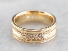 This engraved band is of a perfect heft and shape to feel soft and pleasant on the finger. It is both pretty and sophisticated, and it would be a great wedding or stacking band for a woman who wants a little extra sparkle but works with her hands. Metal: 18K Yellow Gold Gem: 12 Diamonds totaling .36 Carats, F in Color, VVS in Clarity Width of Band: 6.5 mm Height off Finger: 1.9 mm Ring Size: 6 Marks: "AA18K" Stamped on the inside band Fine Jewelry Wedding Rings With Milgrain Detail, Timeless Yellow Gold Band With Decorative Details, Fine Jewelry Engraved Ring With Decorative Band, Luxury Diamond Cut Promise Band, 14k Gold Bands With Diamond Accents, Timeless Yellow Gold Wedding Ring With Decorative Band, Luxury Engraved Promise Ring With Decorative Band, Formal Yellow Gold Diamond Ring With Decorative Band, Luxury Stackable Rings With Thick Band For Wedding