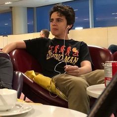 a young man sitting in a chair with headphones on his ears, listening to music