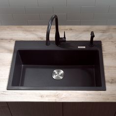 a black kitchen sink sitting on top of a counter next to a cutting board and lemons